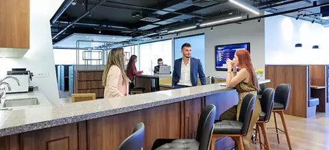 Coworking Space at Qubic Square with people networking and collaborating in a fully stocked kitchen.